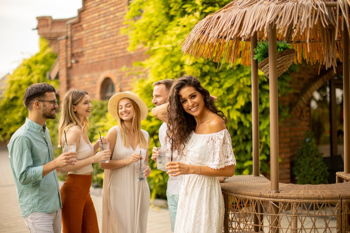 Grupo de amigos brindando y celebrando al aire libre en un ambiente cálido y boho chic