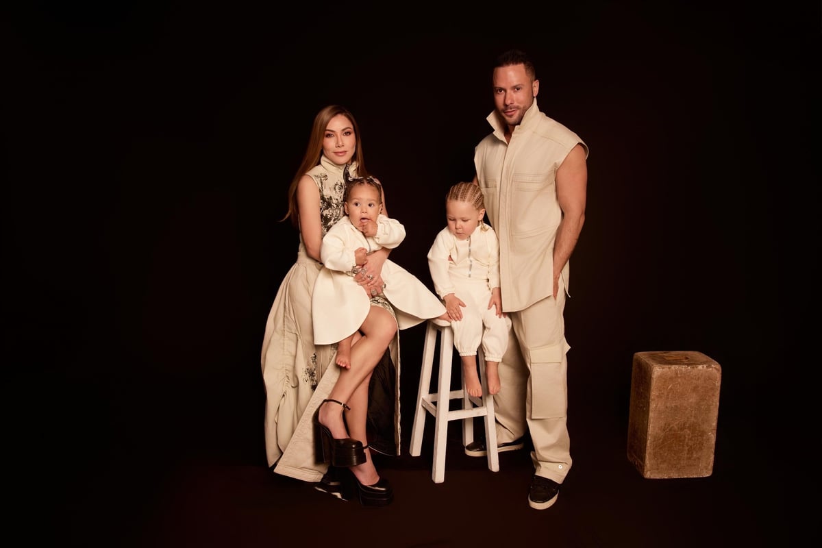 Retrato familiar de dos adultos y dos niños pequeños sobre fondo negro, todos con ropa beige a juego